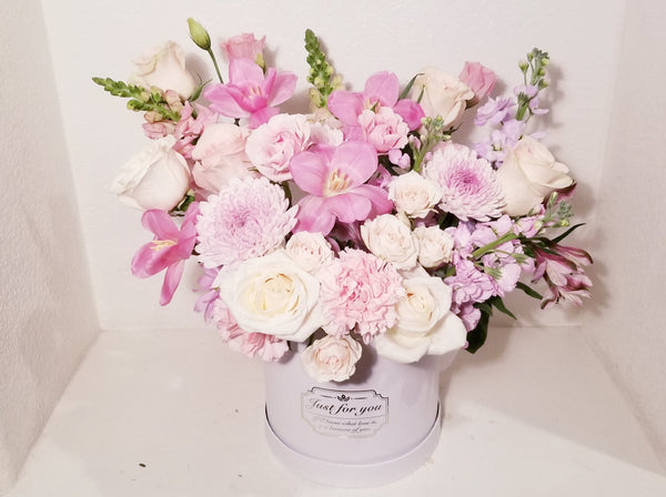 Imagine this gorgeous flower box getting delivered to your door... dreamy! Pink, lavender and creamy flowers such as roses, spray roses, stocks tulips, snapdragons chrysanthemum sophistically arranged with lush greenery and fillers.
