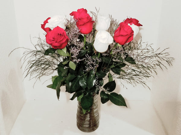 This cheerful design arranged with dozen of red and white roses and fillers, and accented with assorted with greens in clear vase. 