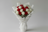 Bouquet of red and white roses in a decorative holder on a gray background
