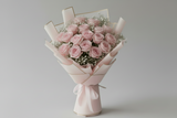 Bouquet of pink roses wrapped in light pink paper on a gray background