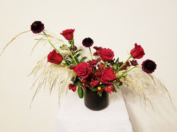 Hanna – Romantic and unique elopement arrangement with gorgeous and fragrant roses, Alstroemerias, Scabiosa, Chrysanthemum Spray and Fresh Pampas Grass and lush greens in black ceramic vase.