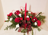 Your loved ones will be feeling merry and bright when they receive this centerpiece of festive holiday spirit. With red roses, red carnations, red hypericum berries and Christmas greens, vibrant red blooms make a bold statement with your holiday decor. Set around a tall red tapper candle and natural pinecone pics, there really is no better way to dress up the table than with the Christmas Candle Centerpiece.