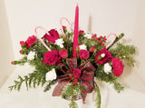 Your loved ones will be feeling merry and bright when they receive this centerpiece of festive holiday spirit. With red roses, red and white carnations, red hypericum berries and Christmas greens, vibrant red blooms make a bold statement with your holiday decor. Set around a tall red tapper candle and natural pinecone pics, there really is no better way to dress up the table than with the Christmas Candle Centerpiece.