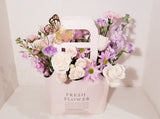Adorable Valentine's Flowers Bag arrangement, which has a stunning mix of lavender, creamy and pink flowers such as roses, spray roses, stocks, Lisianthus,  Mums sophistically arranged with lush greenery and fillers.