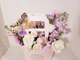Adorable Valentine's Flowers Bag arrangement, which has a stunning mix of lavender, creamy and pink flowers such as roses, spray roses, stocks, Lisianthus,  Mums sophistically arranged with lush greenery and fillers.