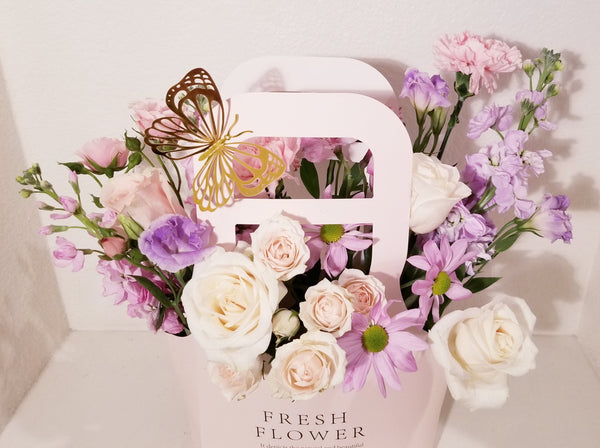 Adorable Valentine's Flowers Bag arrangement, which has a stunning mix of lavender, creamy and pink flowers such as roses, spray roses, stocks, Lisianthus,  Mums sophistically arranged with lush greenery and fillers.