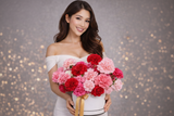 Woman holding a bouquet of flowers against a gray background with bokeh lights