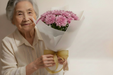 Woman holding a bouquet of yellow flowers against a plain background