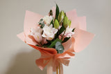 Bouquet of Roselily flowers wrapped in pink paper held by a hand against a neutral background - Fragrant & Long-Lasting)