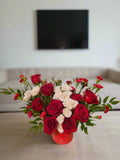 Bouquet of red and white flowers with a heart-shaped balloon on a beige background