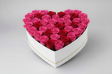 Heart-shaped box filled with red and hot pink roses on a light gray background