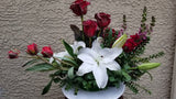 Floral arrangement with red roses and white lilies on a beige background