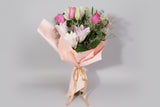 Bouquet of Hot Pink Rose & Fragrant Roselily wrapped in pink paper with a gold ribbon on a white background