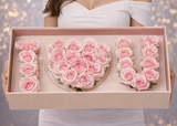 Box of pink roses shaped like a heart held by a person against a blurred background