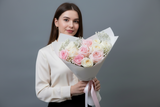 Woman holding a bouquet of flowers against a gray background