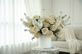 White vase with beige roses and white flowers on a marble surface