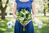 Person in a blue dress holding a bouquet of flowers outdoors.