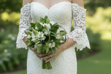 Bride holding a bouquet of green and white flowers in a garden setting