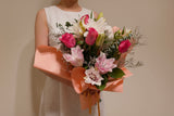 Roses and Roselili Bouquet of flowers held by a person with a neutral background