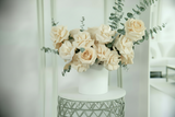 Bouquet of beige flowers in a white vase on a decorative table against a light background