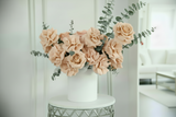 Bouquet of beige roses in a white vase on a marble table with a blurred background