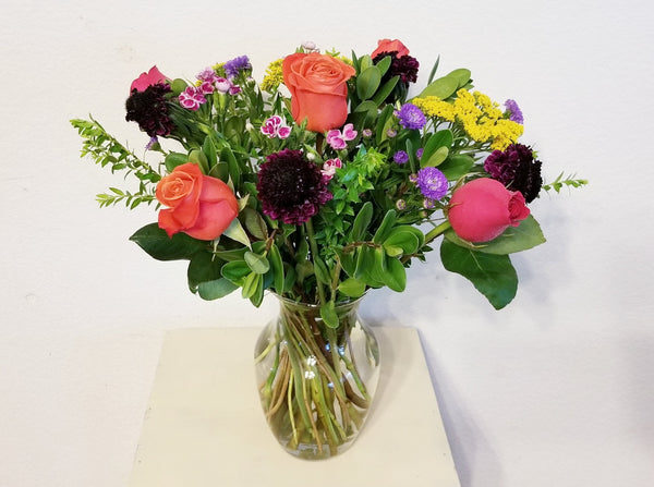 The Sunset Reflections is brilliant and beautiful, featuring hot pink and red/orange roses, Scabiosa, mini carnations, Yarrow, fillers, and premium foliage.