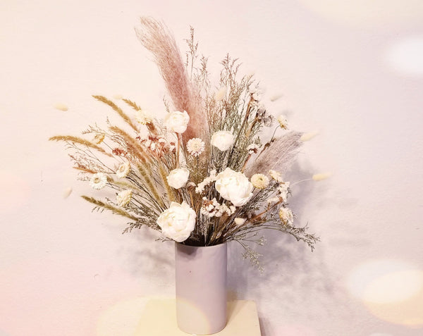 This all dried floral arrangement will last you forever and ever! Designed with a mix of Sola Wood, dried flowers in whites & cream in modern white ceramic speckle vase. 